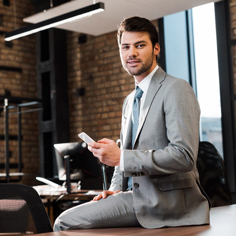 handsome-smiling-businessman-sitting-on-office